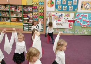 Dzieci tańczą trzymając w rękach białe i czerwone chustki